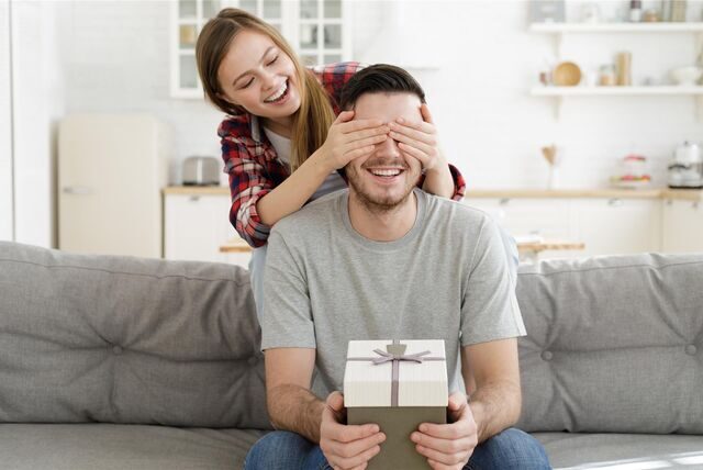 mann wird mit einem geschenk von einer frau überrascht