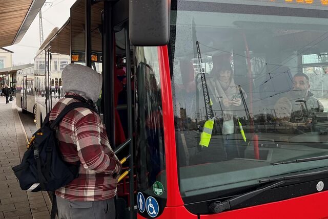 Am Busbahnhof in Unna hält ein VKU-Bus, der vom Fahrer eines privatwirtschaftlichen Unternehmens gesteuert wird. Neben ihm steht in Signalweste ein Streikposten von Verdi, der die Fahrgäste über den laufenden Warnstreik informiert.