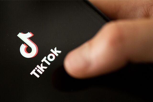 Ein Teenager tippt auf das TikTok-Logo auf einem Smartphone.