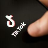 Ein Teenager tippt auf das TikTok-Logo auf einem Smartphone.