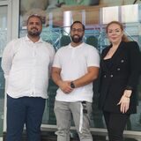 Zwei Männer und eine Frau stehen vor einer Schaufensterscheibe
