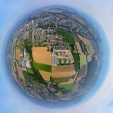 Eine Luftaufnahme von Holzwickede ist so verzerrt, dass es aussieht wie eine Weltkugel mit Himmel ringsherum. In der Mitte treffen Felder und Grünflächen auf Wohngebiete und bebaute Flächen.