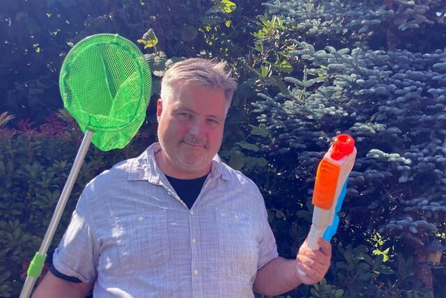 Alexander Spieß mit Kescher und Wasserpistole im Garten.
