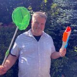Alexander Spieß mit Kescher und Wasserpistole im Garten.