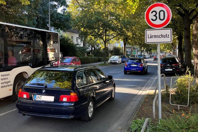 Auf der Friedrich-Ebert-Straße in Unna fahren Autos und ein Bus vorbei an einem Straßenschild mit der Aufschrift „30“ und „Lärmschutz“.