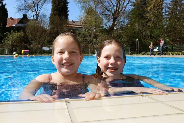 Zwei Mädchen schwimmen bei der Saisoneröffnung im Freibad Dellwig im Wasser