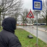 Eine Person mit Kapuze von hinten vor einem Park-and-Ride-Schild an em P+R-Parkplatz am Hafen.