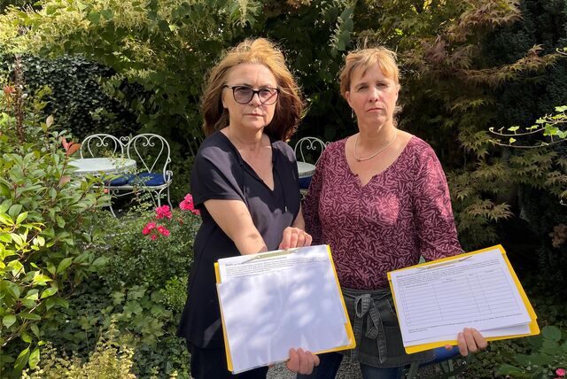 Beate Moller (l.) und Annett Kyncl stehen mit Unterschriftenlisten im Garten des Café Moller
