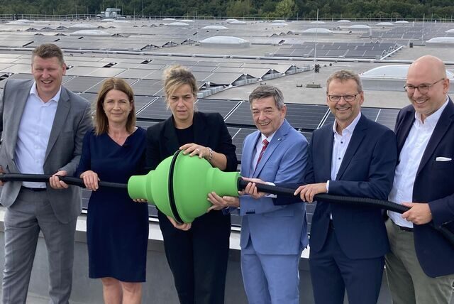 Eine symbolische Stromverbindung auf dem Dach der Metro Logistics in Brassert stellen her (v.l.): Goodman Deutschland-Geschäftsführer Christof Prange, Metro-Arbeitsdirektorin Christiane Giesen, NRW-Wirtschaftsministerin Mona Neubaur, Bürgermeister Werner Arndt, BayWa r.e.-Geschäftsführer Günter Haug und Metro-Logistics-Geschäftsführer Arnd Stoehr.