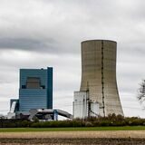Das Kohlekraftwerk Datteln 4 steht mitten in der Landschaft, im Vordergrund ein einzelner Baum, graue Wolken am Himmel.