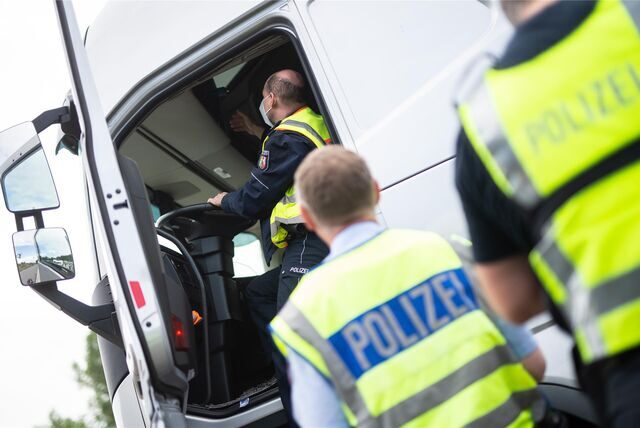 Polizisten kontrollieren einen Lastwagen.