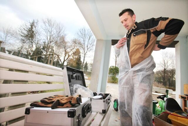 Schädlingsbekämpfer Tim Krause zieht sich einen Schutzanzug für einen Einsatz über.