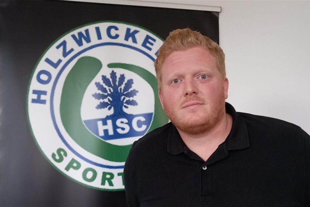 Marius Wetzel steht vor einem Banner mit HSC-Logo. Marius Wetzel steht vor einem Banner mit HSC-Logo.
