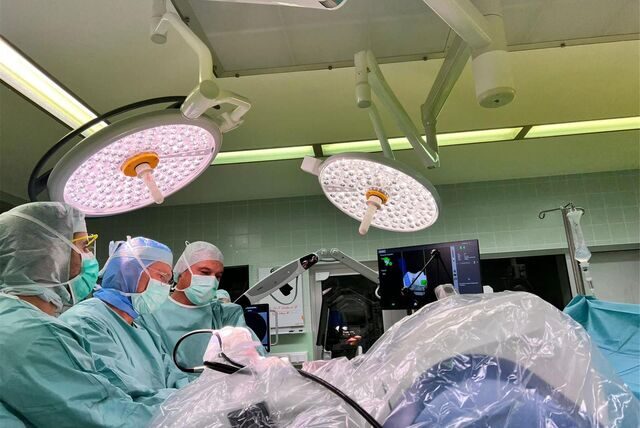 Blick in einen OP, in dem mithilfe eines Roboterarms eine Knieprothese eingesetzt wird