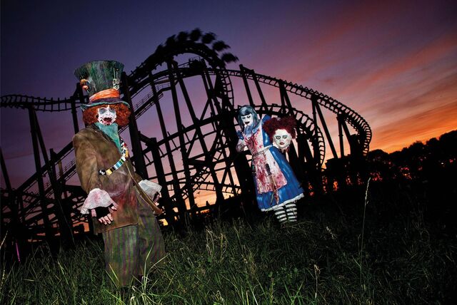 Verkleidete Darsteller im gruseligen Kostüm vor einer Achterbahn beim Halloween Horror Festival im Movie Park Germany in Bottrop.