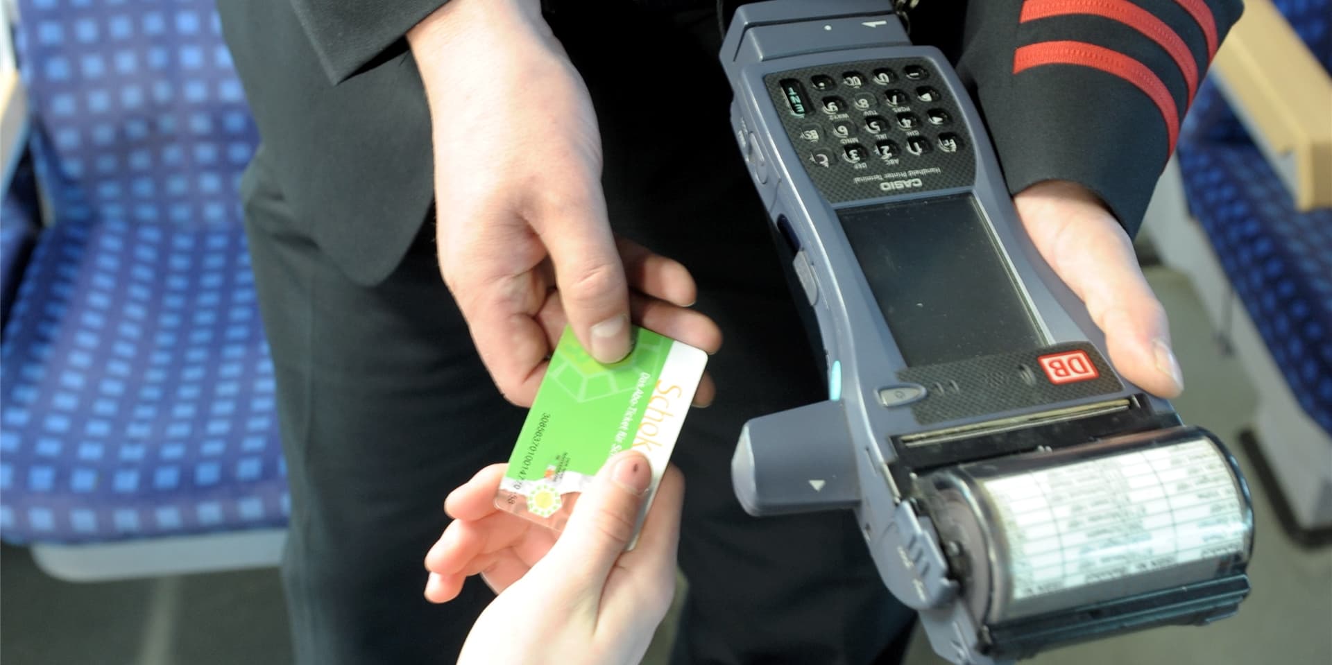Ein Schaffner kontrolliert die Fahrkarte eines Bahnkunden.