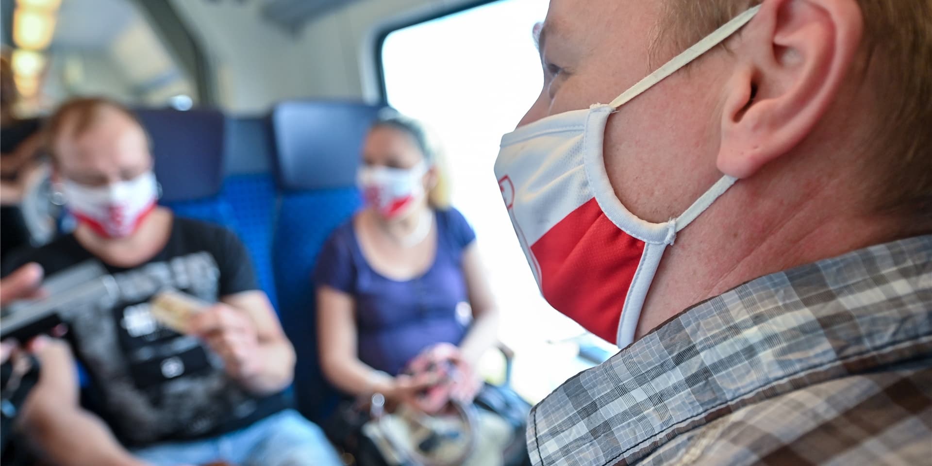 Mann mit Mund-Nasen-Maske in einem Regionalzug