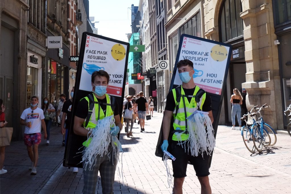 title attribut In Amsterdam werden Mundschutz-Masken an Passanten verteilt.