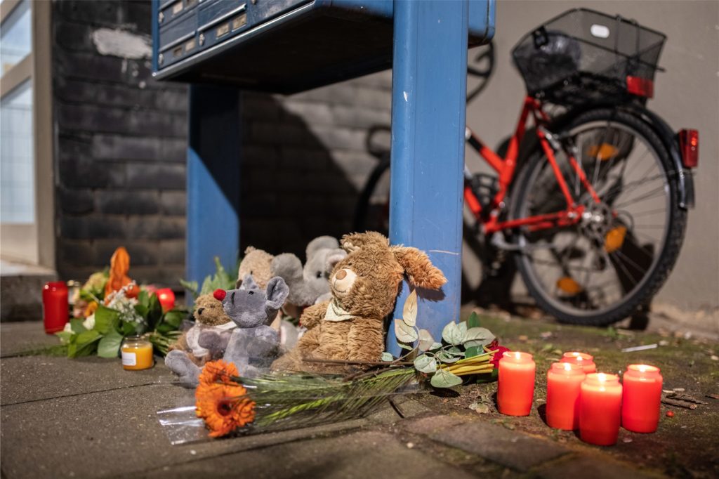 title attribut Teddybären, Kerzen und Blumen liegen und stehen vor einem Haus. Eine 27-jährige Mutter soll in Solingen fünf Kinder umgebracht haben.