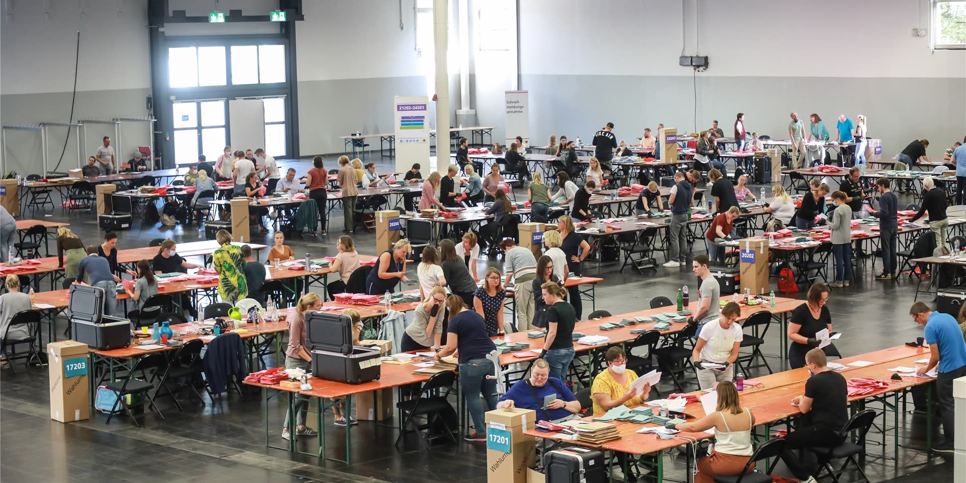 Wahlurne in den Westfalenhallen in Dortmund, im Hintergrund Stimmzettel und Mundschutze