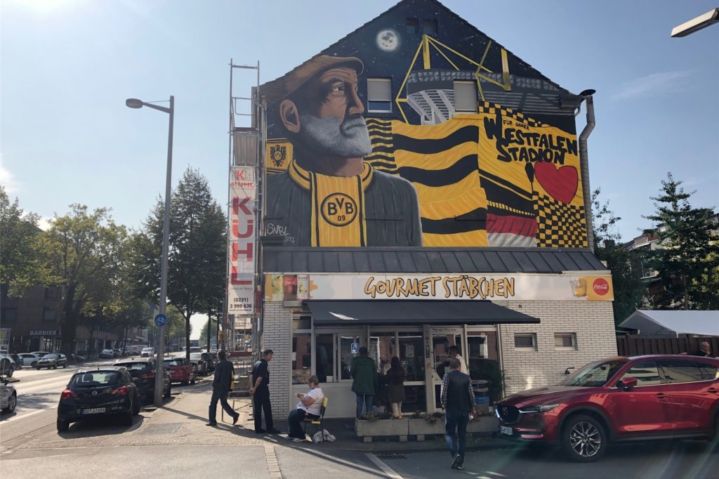 title attribut Über die gesamte Fassade ist das neue schwarzgelbe Wandbild zu sehen.
