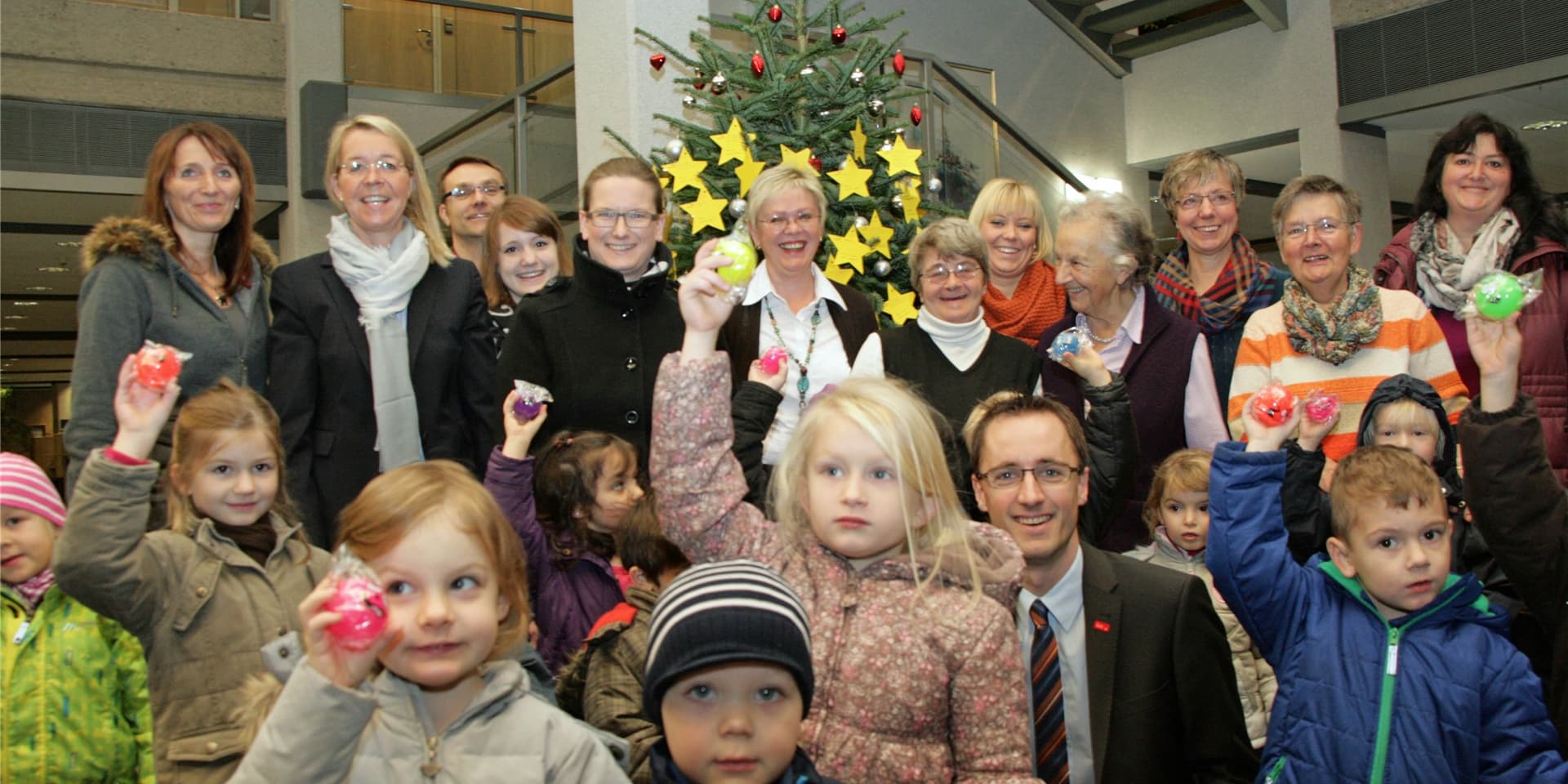 Vertreter der beteiligten Organisationen schmückten im Jahr 2014 in der Sparkassen-Hauptstelle den Weihnachts-Wunschbaum. Die Bienengruppe aus der Kita auf dem Berg half dabei.