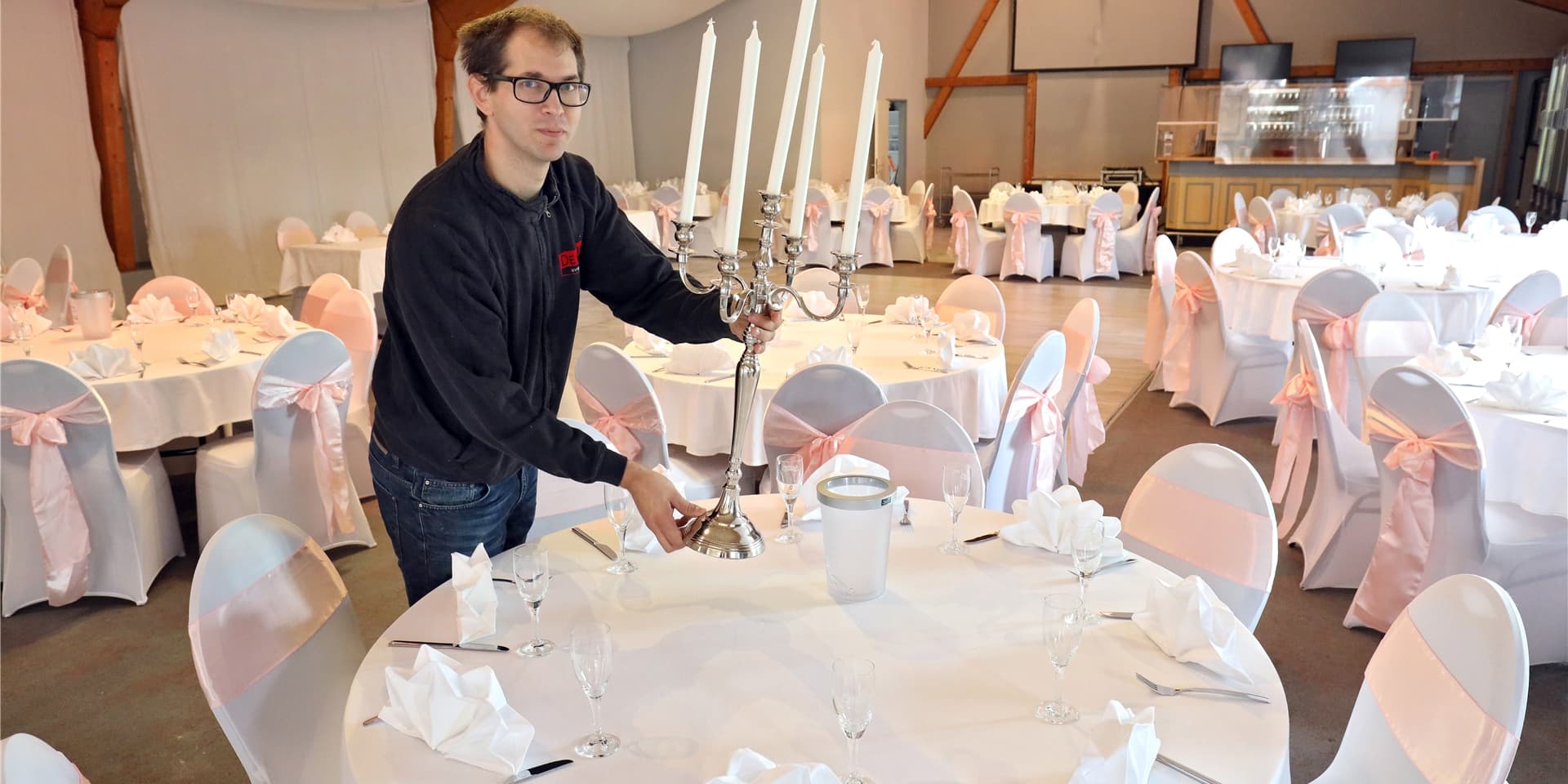 Geschäftsführer Andreas Opitz stellt einen Kerzenleuchter auf einen feierlich gedeckten Tisch.