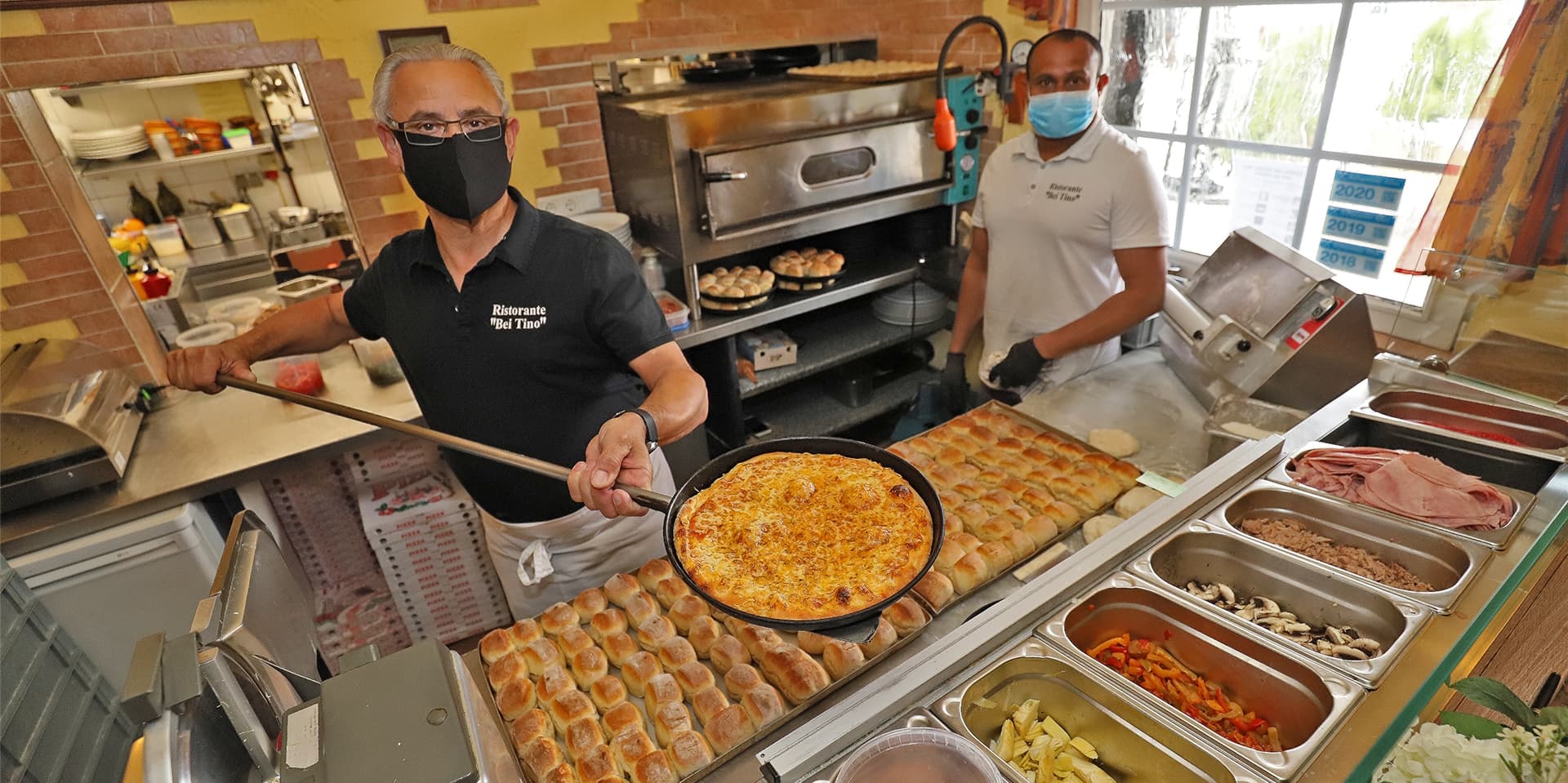 Enrico Mazzoletti backt mit Anbalakan Nadarasa frische Pizza. Vor dem Lockdown konnte sie vor Ort verspeist werden, jetzt können Kunden sich Pizzen und Co. abholen oder liefern lassen.