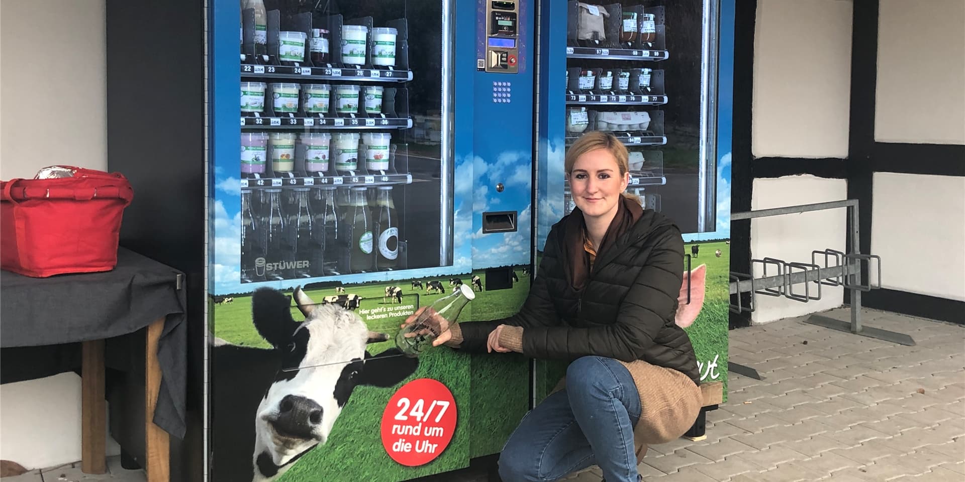 Landwirtin Simone Lategahn hockt vor zwei Automaten mit Produkten aus dem Hofladen.