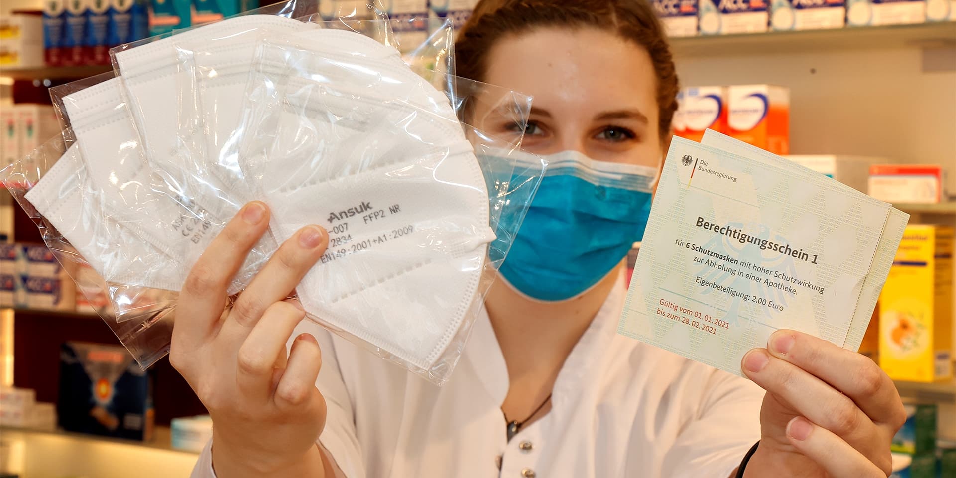 Julia Gropp aus der Rathaus-Apotheke am Alten Markt in Kamen mit sechs FFP2-Masken, die sie an Kunden ausgibt, die einen Berechtigungsschein mitgebracht haben.