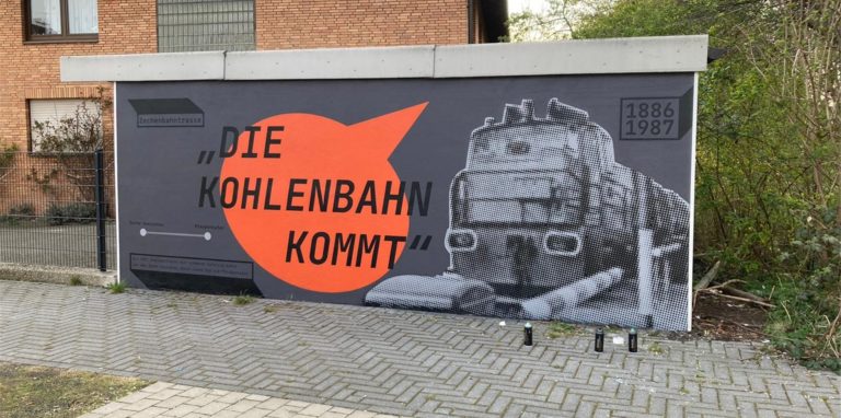 Das Kunstwerk an der Garagenwand erinnert an die Zechenbahn, die bis 1987 durch den Stadtteil führte.