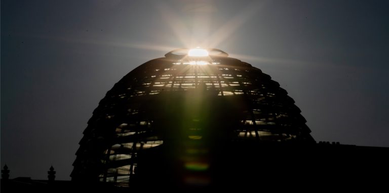 Die Sonne geht hinter der Kuppel des Reichstagsgebäudes auf. Im Roman „Machtergreifung“ kommt ein AfD-Vertreter nach ganz oben.
