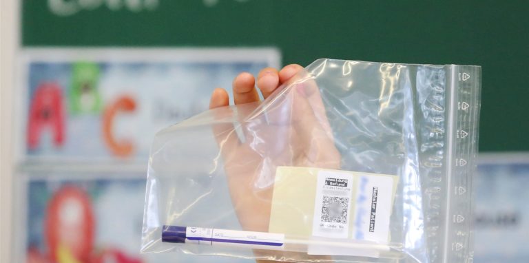 Eine Lehrerin präsentiert einen Lollitest, wie er an den Grundschulen nun verteilt wird.