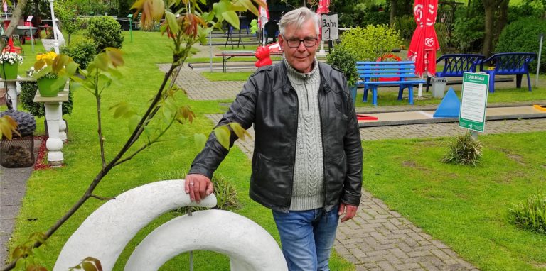 Martin Ketelhut steht während einer ganz kurzen Regenpause auf dem durchnässten Rasen seiner Minigolfanlage. Trotz schlechter Wetterprognose ist die Anlage Pfingstsonntag und -montag geöffnet.
