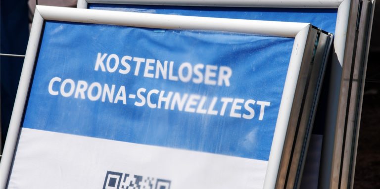 Ein Schild mit der Aufschrift „Kostenloser Corona-Schnelltest“ steht vor einem Testzentrum.