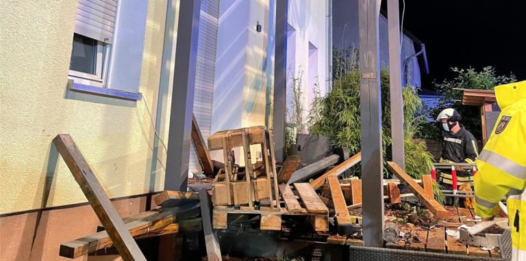 Rettungskräfte stehen neben den Trümmern eines Balkons aus Holz, der mit mehreren Menschen darauf eingestürzt ist.
