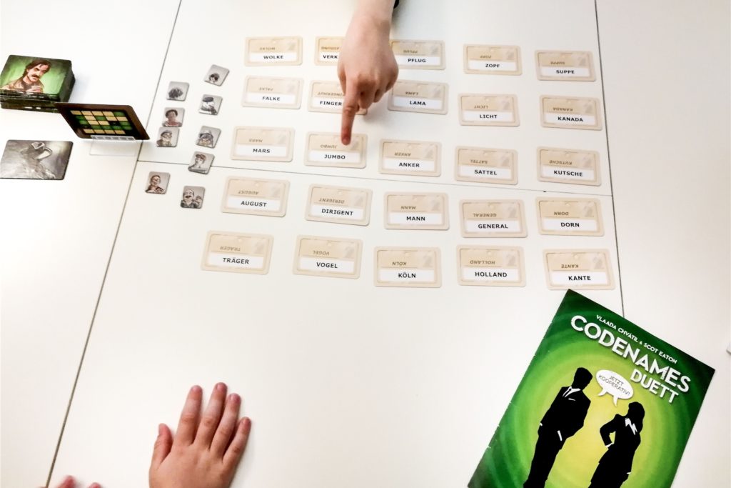 title attribut Das Spiel «Codenames Duett» kann zu zweit oder in zwei kleinen Teams gespielt werden. Mitspieler werden nur mit einem Wort oder einer Zahl auf einen Begriff hingewiesen.