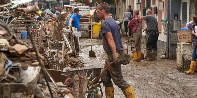 Anwohner und Ladeninhaber versuchen, ihre Häuser vom Schlamm zu befreien und unbrauchbares Mobiliar nach draußen zu bringen.