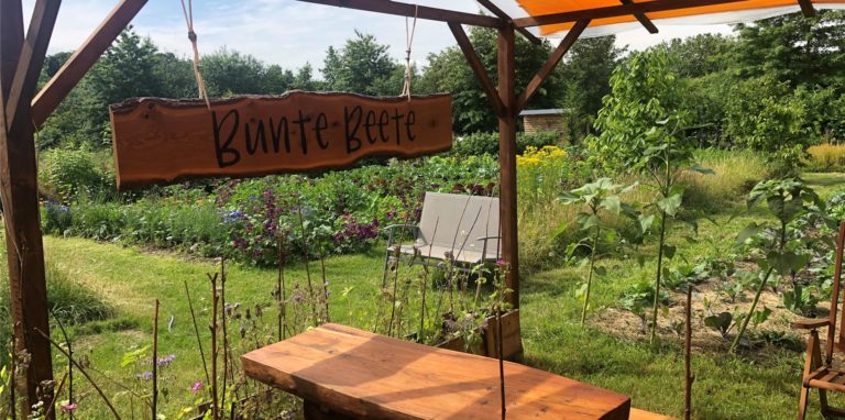 Blick auf die Beete der Permakultur Ruhr. Im Vordergrund die gemütlich Sitzgarnitur vor dem 2021 eröffneten Imbiss.