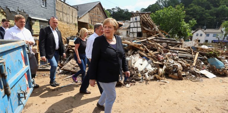 Bundeskanzlerin Angela Merkel (CDU, M) und der Ministerpräsident von Nordrhein-Westfalen Armin Laschet (CDU, 3.v.l) besichtigen ein Lager mit Lebensmitteln bei ihrem Besuch im vom Hochwasser betroffenen Gebiet von Bad Münstereifel.