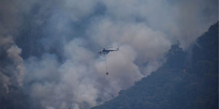 Ein Hubschrauber transportiert Löschwasser, um einen Waldbrand in der Türkei zu löschen.