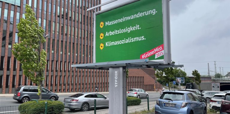 Ein Plakat im Design der Grünen ist im Schatten des U-Turms zu sehen. Doch das Plakat ist Teil einer Schmähkampagne gegen die Grünen.