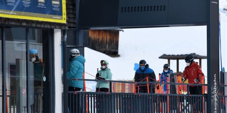 Wintersportler stehen in Tirol mit Mund-Nasen-Schutz an einem Skilift Schlange.