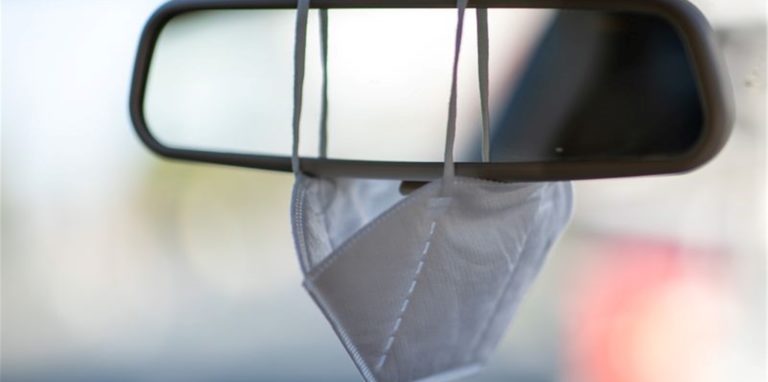 Eine FFP2-Maske hängt am Rückspiegel eines Autos. (Symbolbild)