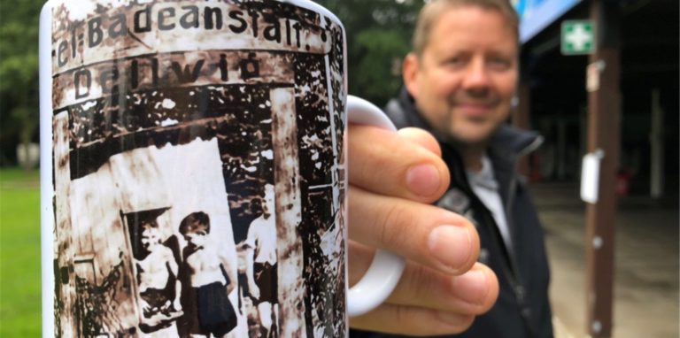 Geschäftsführer Dirk Weise zeigt die neue Sammeltasse, mit der der Förderverein des Freibads Dellwig sicherlich wieder auf großes Interesse stoßen wird.