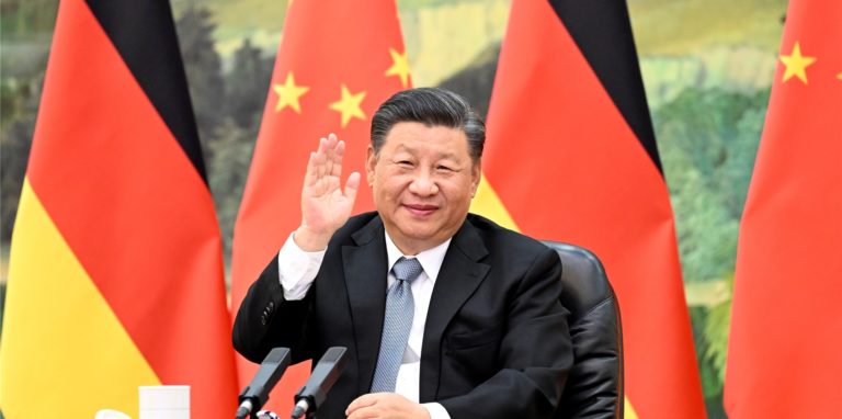Xi Jinping, Präsident von China, sitzt vor den Flaggen von China und Deutschland.