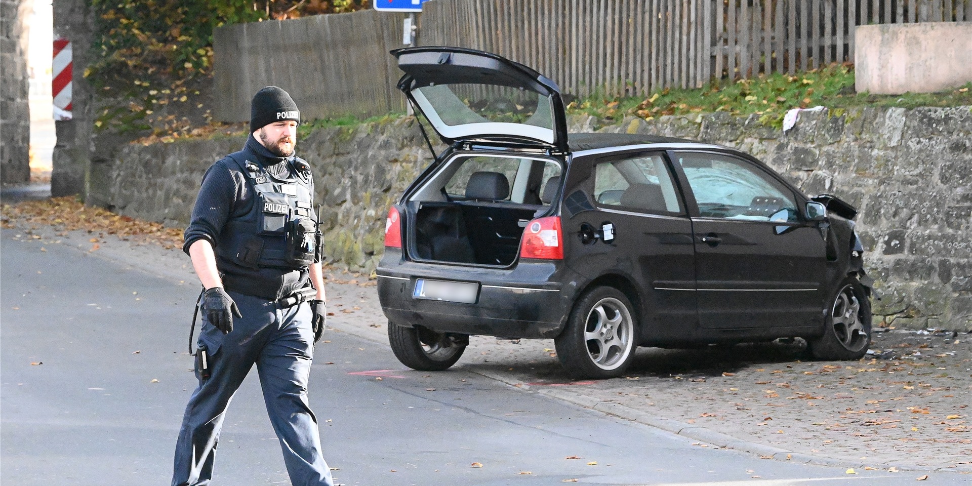 Ein Polizist geht an einem VW Polo vor einer Kindertagesstätte im Ortsteil Gertenbach vorbei. Dort soll ein Autofahrer absichtlich in eine Gruppe Kinder gefahren sein.