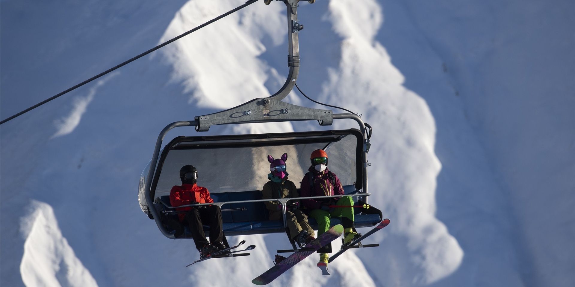 Skifahrer tragen FFP2-Schutzmasken in einem Sessellift im Skigebiet Silvretta Arena in Samnaun. Das Schweizer Samnaun betreibt mit Ischgl in Tirol (Österreich) ein gemeinsames Skigebiet.