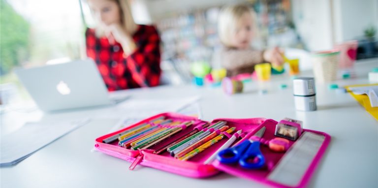 Eine Mutter hilft ihren Kindern bei den Schulaufgaben, während sie selbst am Computer arbeitet.