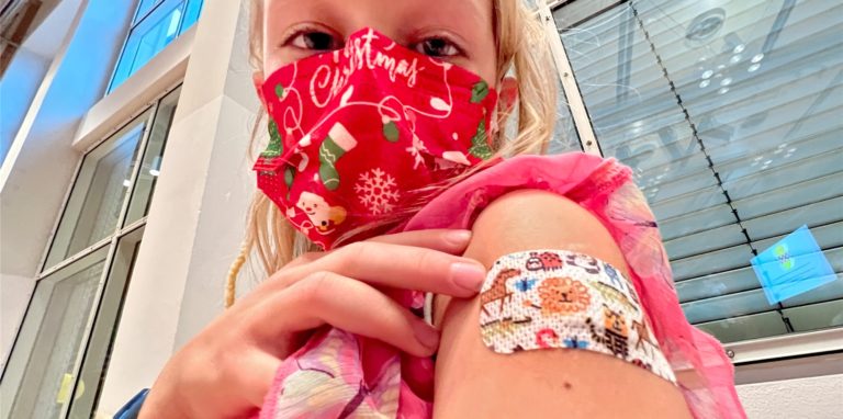 Henrietta zeigt vor der Stadthalle Kamen stolz ihr Pflaster nach ihrer Impfung gegen Corona. Die Stadt erweiterte jetzt ihren nächsten Impftermin, der zunächst nur für Kinder vorgesehen war.